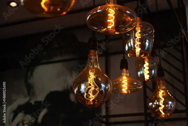 Obraz Decorative incandescent lamps suspended from the ceiling and glowing in the dark.