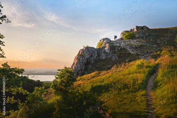 Fototapeta A man with a baby carrier on his back enjoying the view of the South Moravian landscape in the evening light.