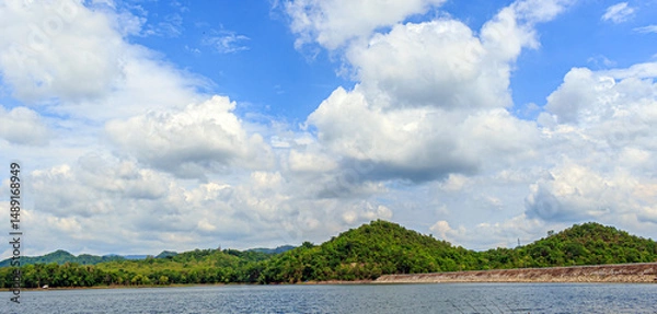 Fototapeta White clouds in the blue sky above the reservoir