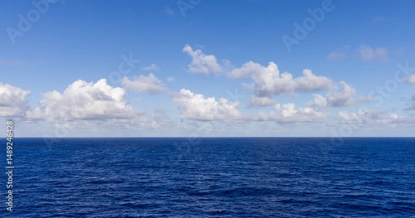 Fototapeta Serene Ocean View Under a Bright Blue Sky and Fluffy Clouds