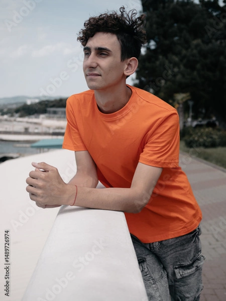Fototapeta A young attractive student is walking on the embankment.