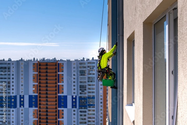 Fototapeta Rope access specialist washes the facade of a building
