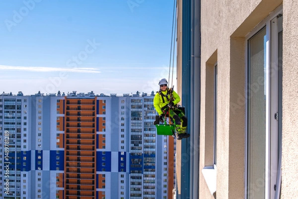 Fototapeta Rope access specialist washes the facade of a building