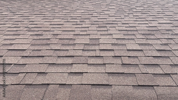 Fototapeta A detailed shot of overlapping gray roof shingles, forming a uniform, textured pattern that extends across the entire surface.