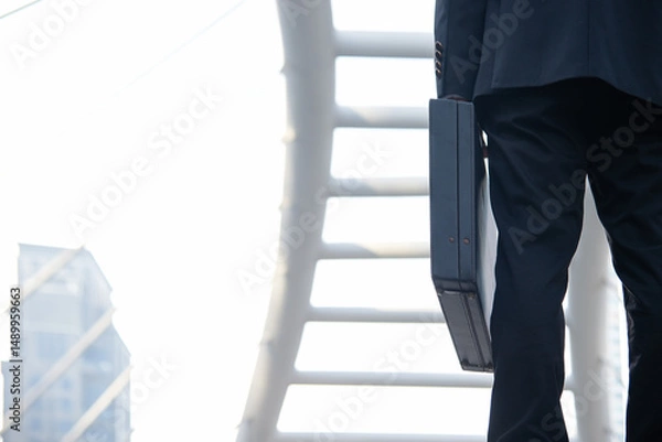 Fototapeta Close up hand holding business bag on the street. Unrecognizable businessman walking with a briefcase in a modern office. Business