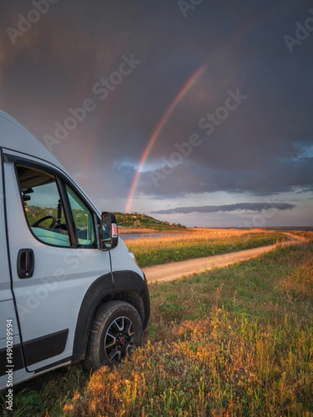 Obraz portrait view to head of white van and rainbow in dramatic sky