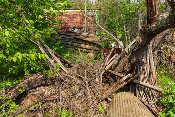 Obraz Junk in a village yard - a pile of branches and wooden planks. Abandoned place in the countryside, summer sunny day