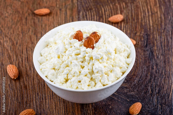 Obraz Fresh cottage cheese and some almonds in a white bowl.