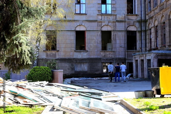 Obraz War in Ukraine. Broken windows in the destroyed building of the medical university after the Russian missile attack. The debris of the building is piled up.
