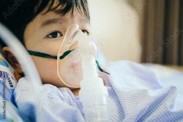 Fototapeta Boy 4 years old , inhale medication by inhalation mask to cure Respiratory Syncytial Virus (RSV) on hospital bed. Admitted patient boy inhalation therapy.