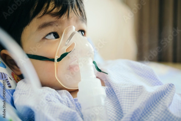 Fototapeta Boy 4 years old , inhale medication by inhalation mask to cure Respiratory Syncytial Virus (RSV) on hospital bed. Admitted patient boy inhalation therapy.