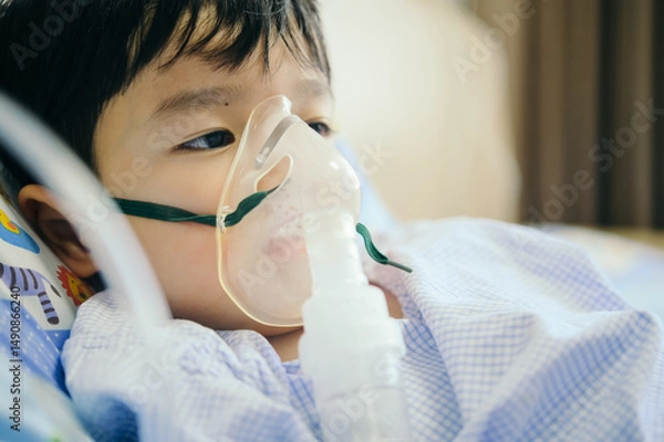 Fototapeta Boy 4 years old , inhale medication by inhalation mask to cure Respiratory Syncytial Virus (RSV) on hospital bed. Admitted patient boy inhalation therapy.
