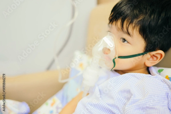 Fototapeta Boy 4 years old , inhale medication by inhalation mask to cure Respiratory Syncytial Virus (RSV) on hospital bed. Admitted patient boy inhalation therapy.
