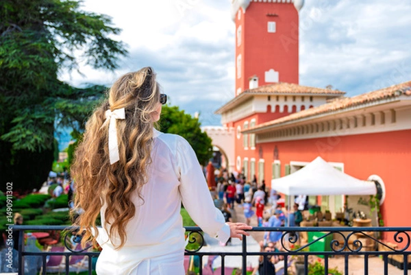 Obraz Woman posing at Chateau de Cremat with red building, and people visiting