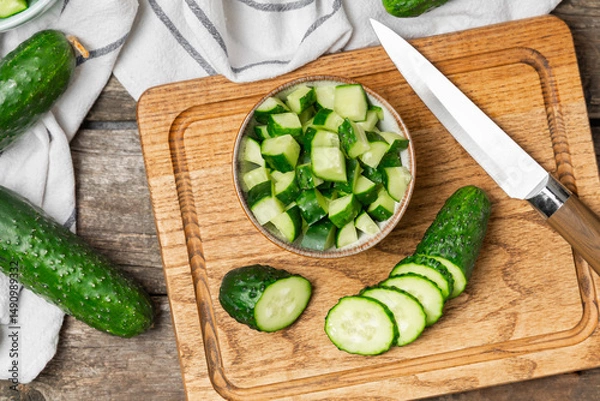 Fototapeta Cucumber on wooden background. Slice of cucumber on background. Fresh organic green cucumbers gherkin. Vegan. Salad ingredient. Farm vegetables. Cut vegetables with knife. Space for text. Copy space