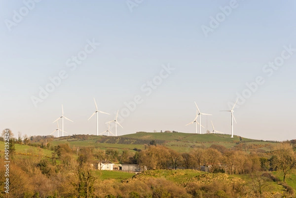 Fototapeta A group of wind turbines are on a hillside