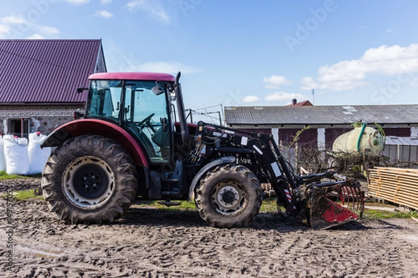 Fototapeta Agricultural machineryand equipment. Tractor with front loader for manure. The yard of a dairy farm. Podlaskie, Poland.