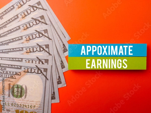 Fototapeta Top view sticky note and banknotes with the word APPOXIMATE EARNINGS on a orange background