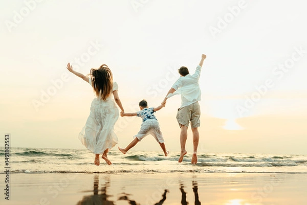 Fototapeta Family jumping happily with their hands raised, having fun on the beach with family during a holiday, travel, long weekend, summer or any other holiday. They are happy to spend time together.