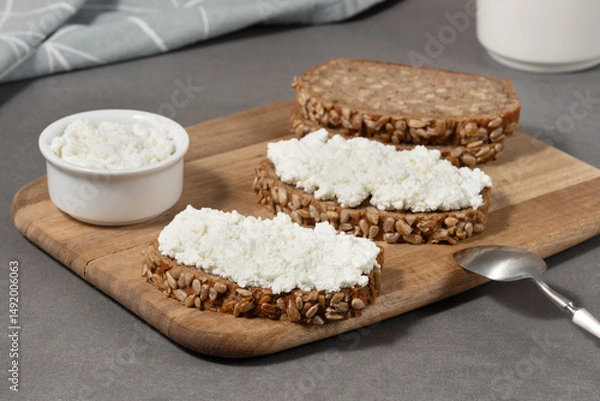Fototapeta Delicious rye bread topped with cottage cheese on a wooden board in a modern kitchen setting