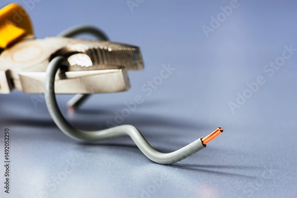 Obraz Installation copper electrical wire with pliers on an industrial, metallic grey surface, minimalist composition