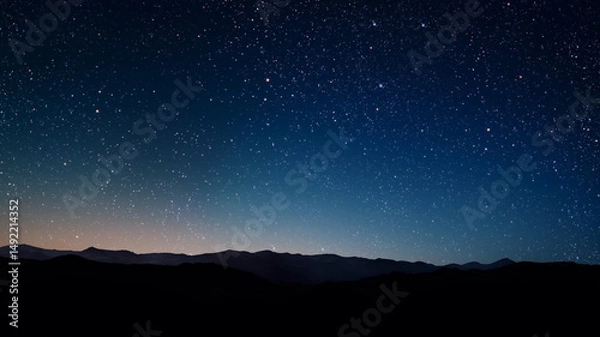 Obraz a a movement of stars in the night sky with the view of mountains.