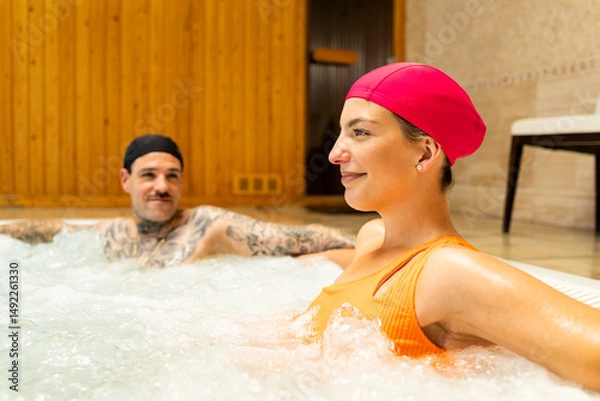 Fototapeta A couple in their 30s and 40s enjoys a day at a spa. The couple is sitting in a hotel's whirlpool. Image of couples in a whirlpool whirlpool.