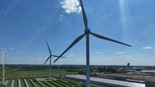 Obraz Wind turbines in a green field under a clear blue sky.