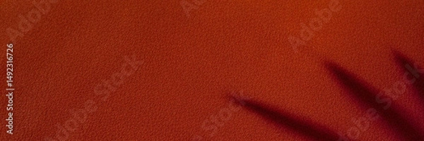 Fototapeta Tropical palm leaf shadow on warm textured red fabric for natural and artistic banner and header design