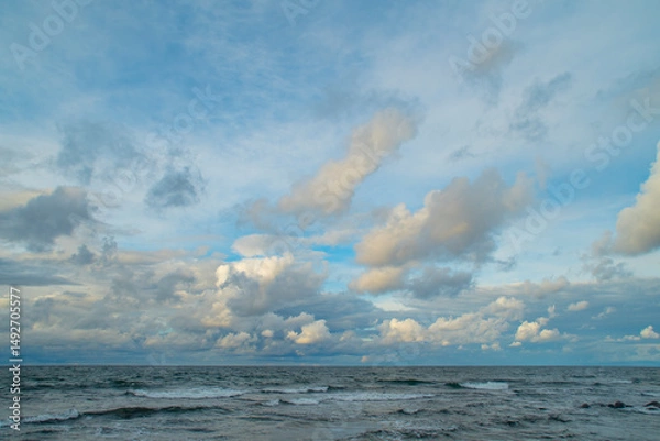 Fototapeta Dark sky over the sea. Low clouds over the water in the bay. Background with a tense panorama of nature before a storm at sunset.