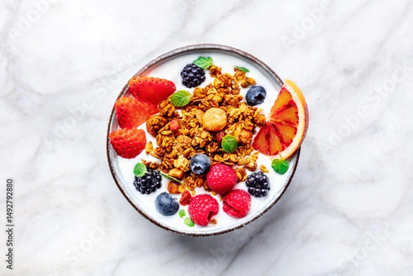 Fototapeta Granola with yogurt and fresh fruit. Organic gourmet muesli with ingredients, overhead flat lay shot on a marble table