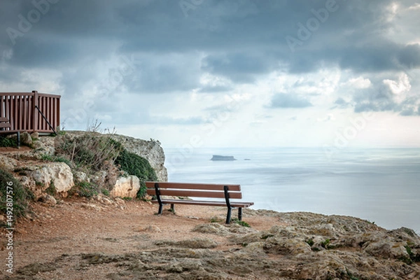 Fototapeta Lonely bench on the edge of cliff on sunny day in Malta. Dingli cliff's, Malta.
