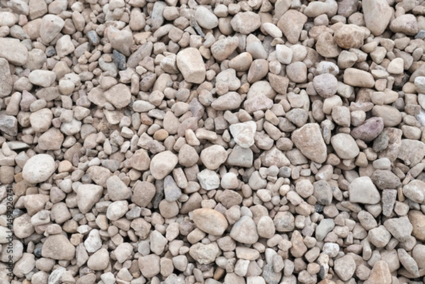 Fototapeta Textured surface of small gravel stones in various shades of gray and beige, creating a natural background for landscaping, construction, or decorative purposes. Copy space