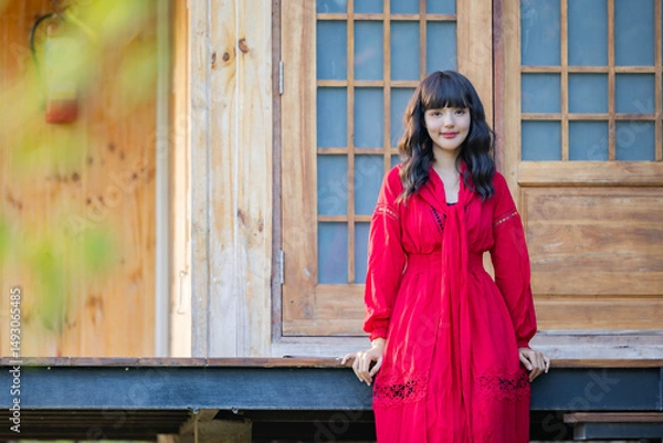 Obraz Asian woman in red dress resting carefree, relaxing on sunny day. Beautiful woman smiling at the park.
