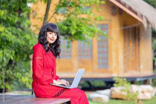 Obraz Beautiful asian businesswoman sitting on the terrace with laptop on legs. Woman working from home using computer laptop.