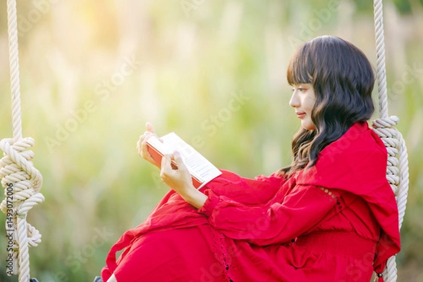 Obraz Side view young calm happy woman wear a red dress, she reading book study rest relax spend time in nature.