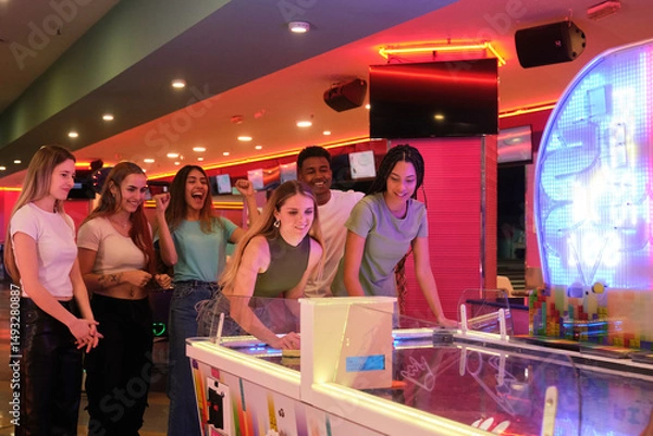 Obraz Group of young people enjoying a game of air hockey in a vibrant arcade