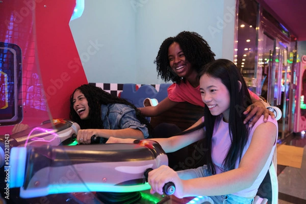 Obraz Three friends enjoying their time together playing arcade game in an amusement park