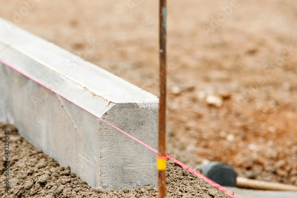 Obraz Close-up of builder hands laying new chamfer kerb on semy-dry concrete mix during new residential road construction