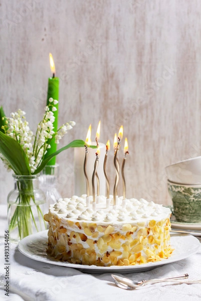 Fototapeta Birthday sour cream and honey cake made of thin layers, decorated with almond petals and candles.