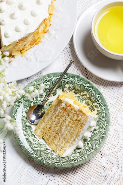Fototapeta Birthday sour cream and honey cake made of thin layers, decorated with almond petals and candles.