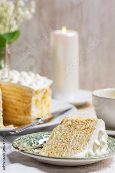 Fototapeta Birthday sour cream and honey cake made of thin layers, decorated with almond petals and candles.