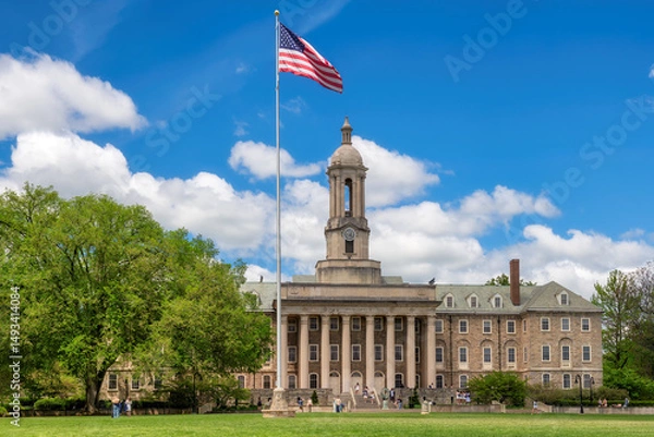 Fototapeta The Old Main building on the campus of Penn State University and American flag in spring sunny day, State College, Pennsylvania.