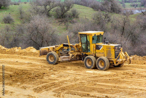 Fototapeta Motor grader on a construction site. Road construction. Leveling the road