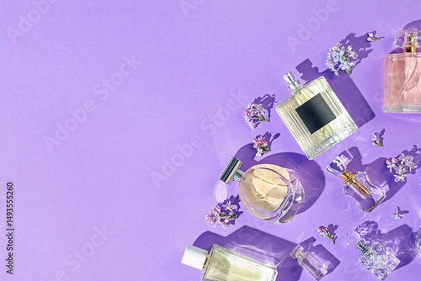 Fototapeta Flat lay composition with perfume bottles and lilac flowers on violet background. Space for text