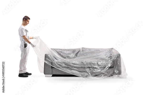 Fototapeta House painter covering a sofa with a plastic drop cloth