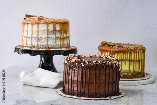 Fototapeta Assorted Gourmet Cakes including Caramel Fig, Pistachio Caramel, and Chocolate cake with napkin side view of assortment of elegant classic cafe desserts