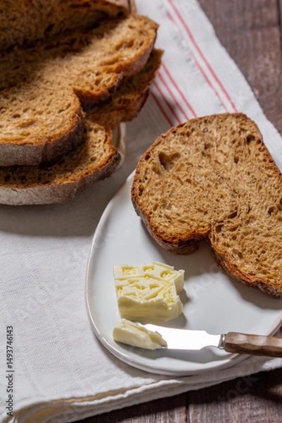 Fototapeta Homemade artisan bread with butter on a light background.