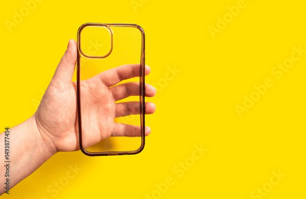 Fototapeta Old and dirty phone case in hand against bright yellow background, showcasing clean design and modern aesthetics, ideal for smartphone protection and style enhancement