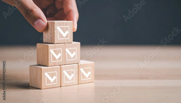 Obraz hand placing a wooden block on top of a pyramid made up of other wooden blocks